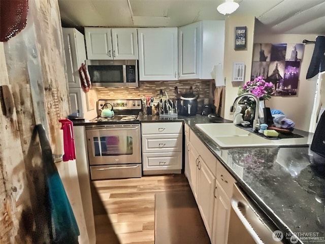 kitchen with tasteful backsplash, wood finished floors, stainless steel appliances, white cabinetry, and a sink