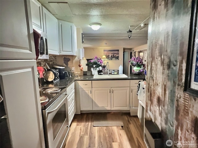 kitchen featuring appliances with stainless steel finishes, light wood-type flooring, a sink, and white cabinets