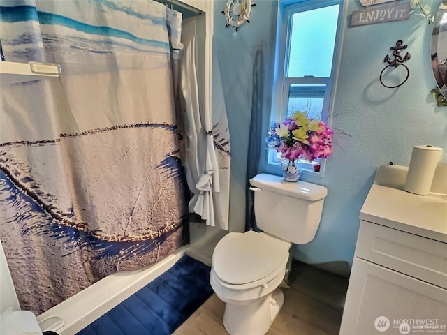 full bath with a shower with curtain, a textured wall, vanity, and toilet