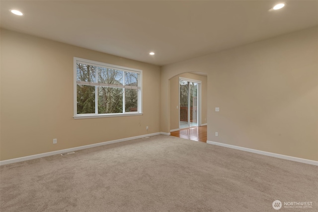 unfurnished room featuring arched walkways, carpet floors, baseboards, and recessed lighting