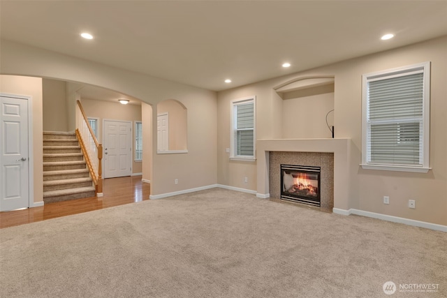 unfurnished living room featuring carpet, stairway, baseboards, and recessed lighting