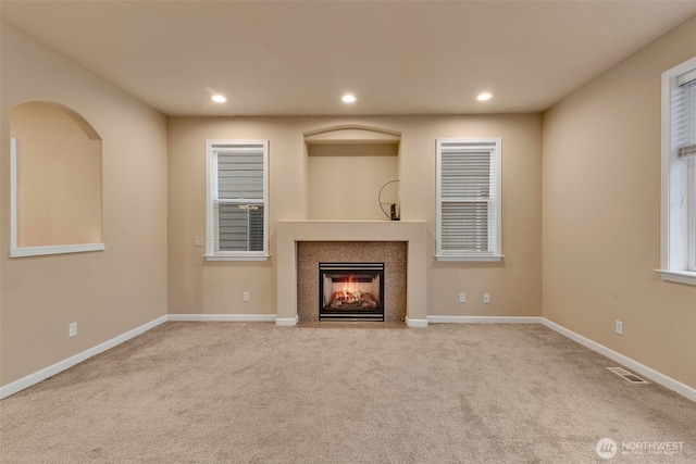 unfurnished living room with baseboards, a fireplace with flush hearth, visible vents, and recessed lighting