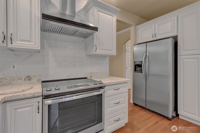 kitchen with tasteful backsplash, wall chimney range hood, appliances with stainless steel finishes, and white cabinets