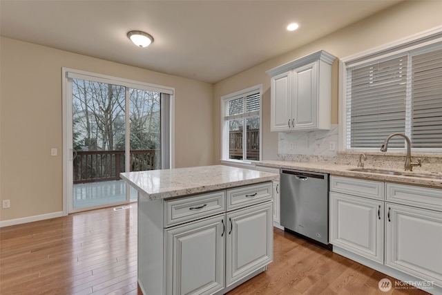 kitchen with decorative backsplash, dishwasher, light wood-type flooring, white cabinetry, and a sink