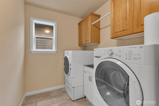 washroom featuring baseboards, cabinet space, and washer and dryer