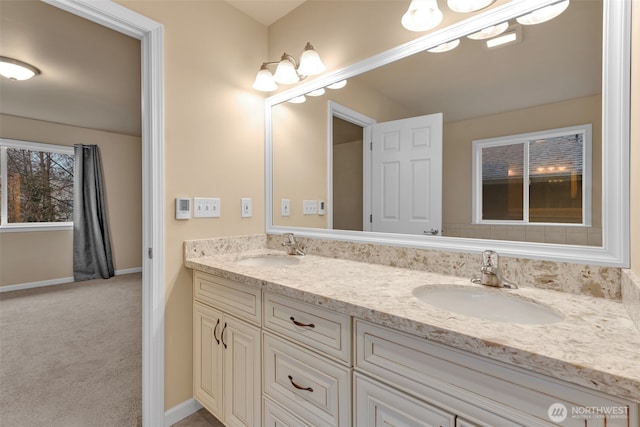 bathroom with double vanity, a sink, and baseboards