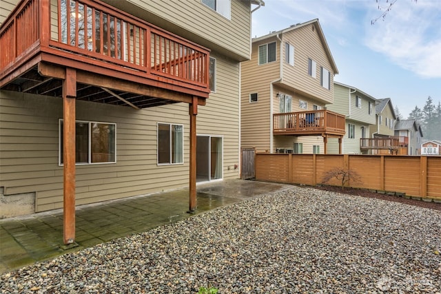 rear view of house featuring a wooden deck, a patio area, fence, and a residential view