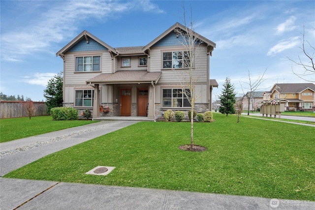 craftsman-style house featuring stone siding, driveway, a front lawn, and fence