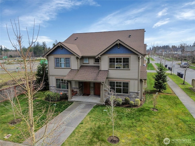 craftsman inspired home featuring stone siding, a porch, a front lawn, and roof with shingles