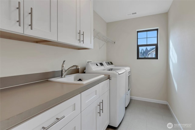 washroom featuring visible vents, baseboards, cabinet space, independent washer and dryer, and a sink