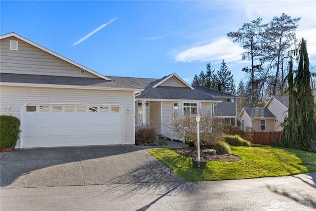 ranch-style home with an attached garage, a shingled roof, fence, driveway, and a front yard