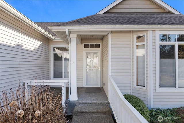 view of exterior entry featuring a shingled roof