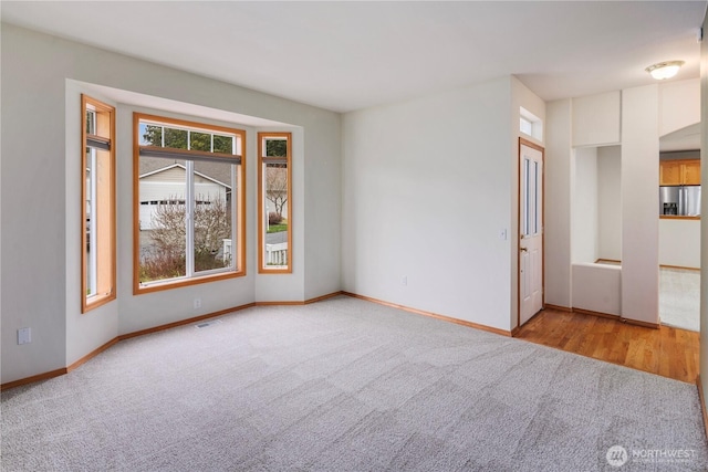 unfurnished room featuring carpet, visible vents, and baseboards