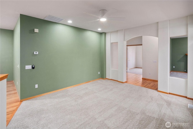 carpeted spare room featuring visible vents, arched walkways, baseboards, ceiling fan, and recessed lighting