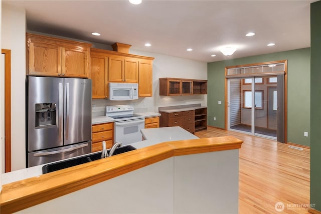 kitchen featuring brown cabinets, recessed lighting, light countertops, light wood-type flooring, and white appliances