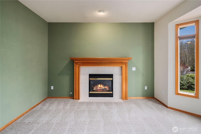 unfurnished living room with carpet floors, a tile fireplace, and baseboards