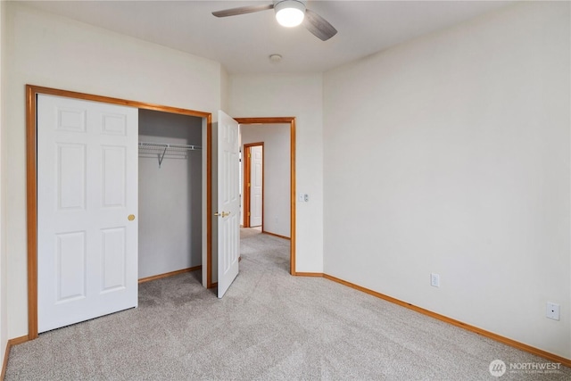 unfurnished bedroom featuring carpet floors, a closet, baseboards, and a ceiling fan