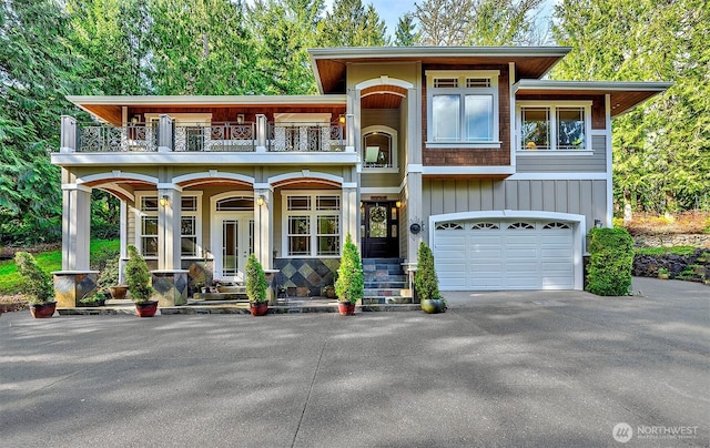 view of front facade with board and batten siding, driveway, a balcony, and an attached garage