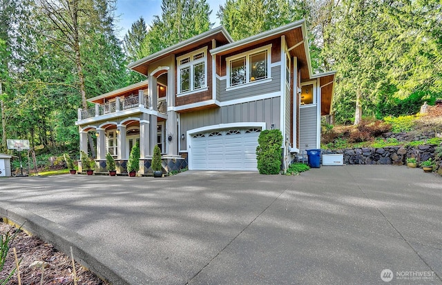 view of front of house with board and batten siding, driveway, a balcony, and an attached garage