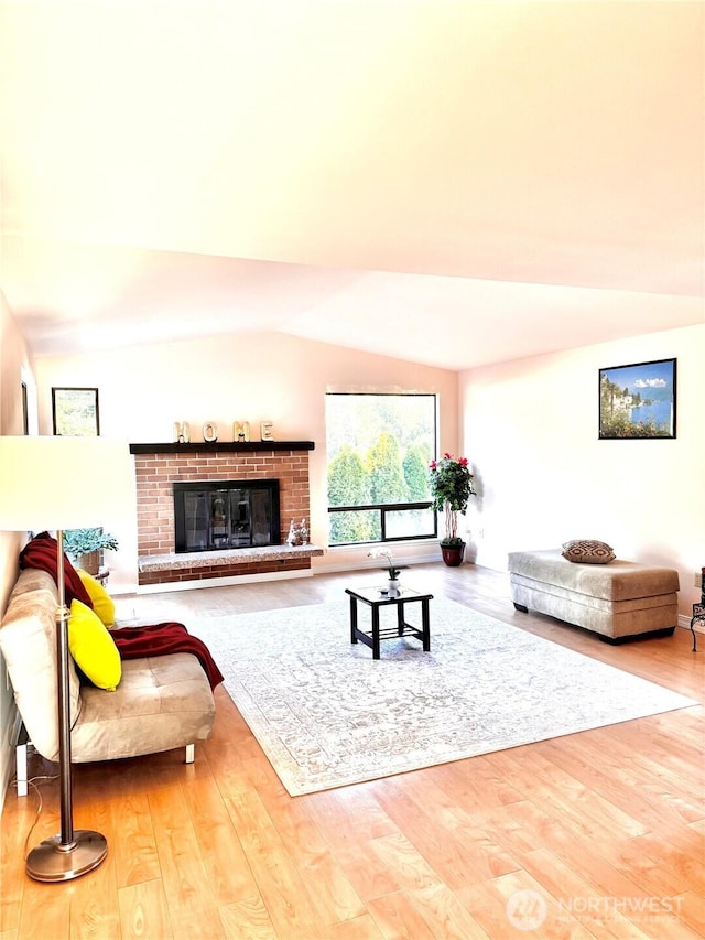 living area featuring lofted ceiling, a brick fireplace, and wood finished floors