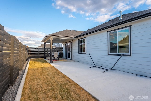 rear view of house featuring a patio, a lawn, and a fenced backyard