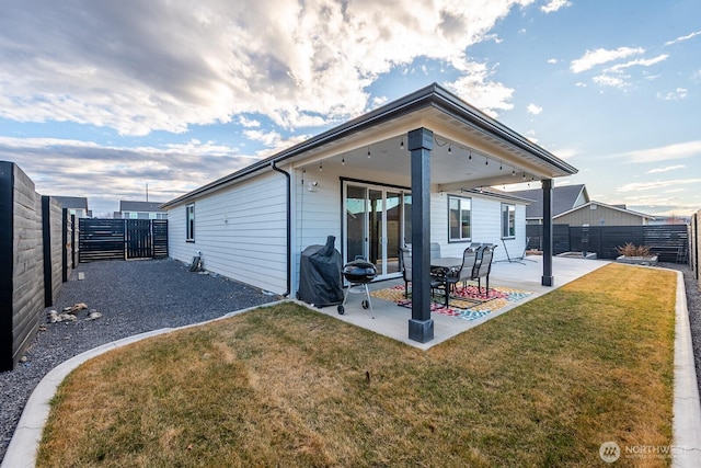 back of property featuring a fenced backyard, a patio, and a lawn