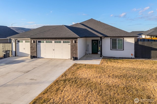 single story home with roof with shingles, concrete driveway, a front yard, fence, and a garage