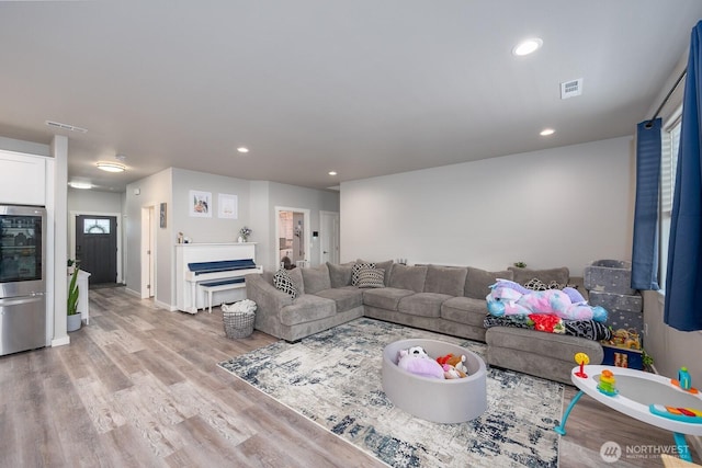 living area with recessed lighting, baseboards, visible vents, and light wood finished floors