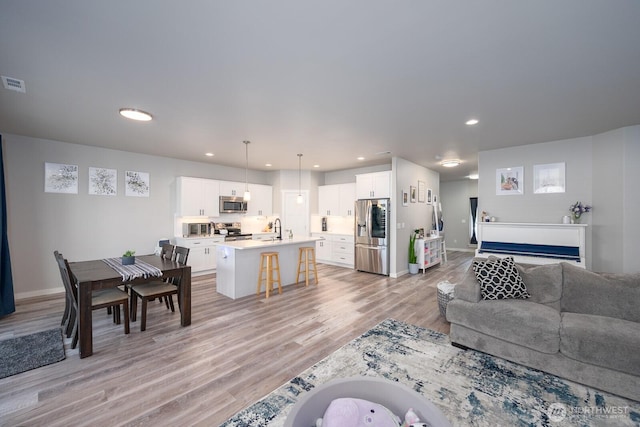 living area featuring baseboards, recessed lighting, visible vents, and light wood-style floors