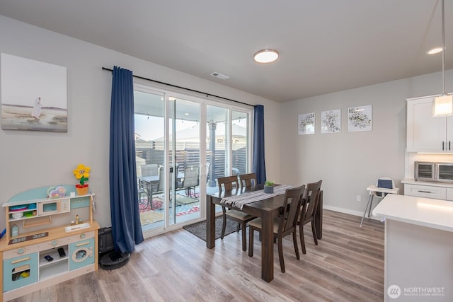 dining space featuring light wood-type flooring, baseboards, visible vents, and a toaster