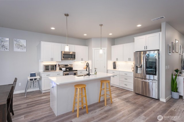 kitchen featuring a breakfast bar, visible vents, backsplash, appliances with stainless steel finishes, and a sink