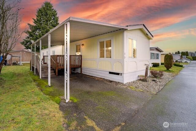 view of home's exterior with a yard, an attached carport, and driveway