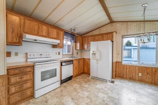 kitchen with wooden walls, white appliances, brown cabinetry, and under cabinet range hood