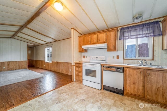 kitchen with a wealth of natural light, wainscoting, a sink, white appliances, and under cabinet range hood