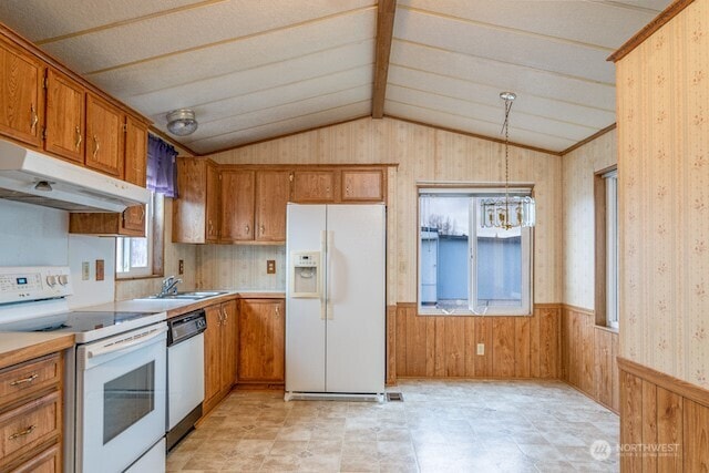 kitchen with white appliances, brown cabinetry, wainscoting, vaulted ceiling, and under cabinet range hood