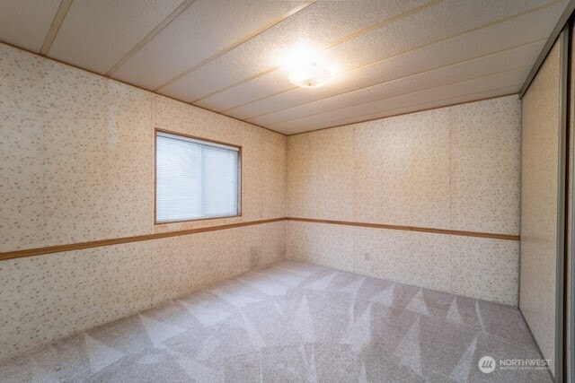 carpeted empty room with wallpapered walls