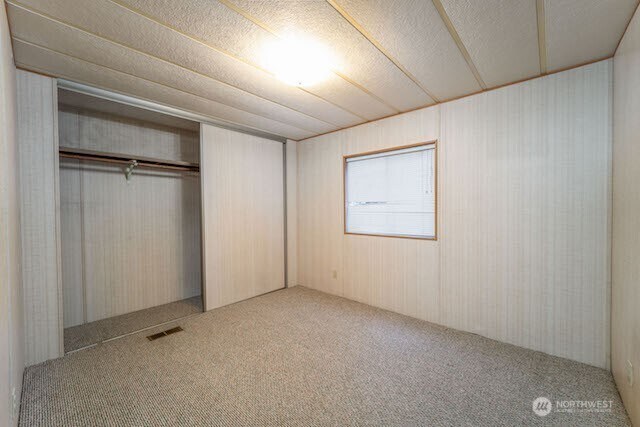 unfurnished bedroom with carpet, a closet, visible vents, and a textured ceiling