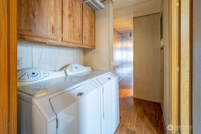 laundry area featuring cabinet space, washing machine and clothes dryer, and wood finished floors