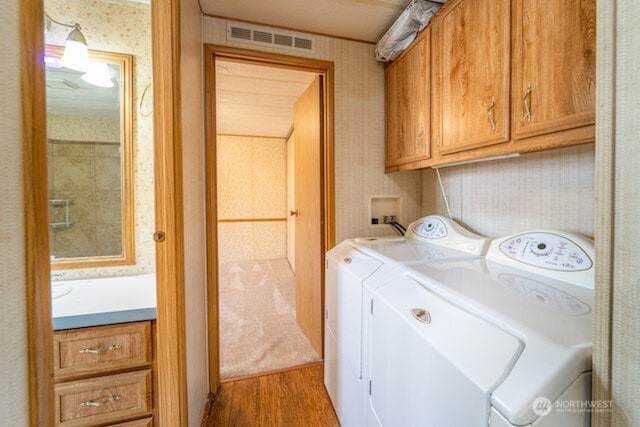 washroom with cabinet space, visible vents, wallpapered walls, and washing machine and clothes dryer