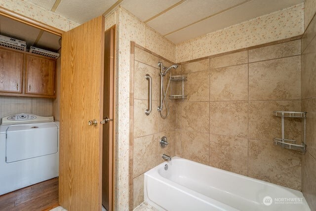 bathroom with washer / dryer and shower / washtub combination