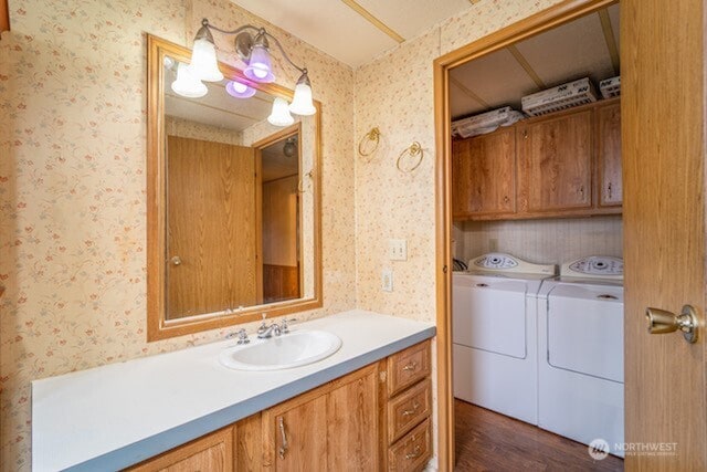 bathroom with washing machine and dryer, vanity, and wallpapered walls