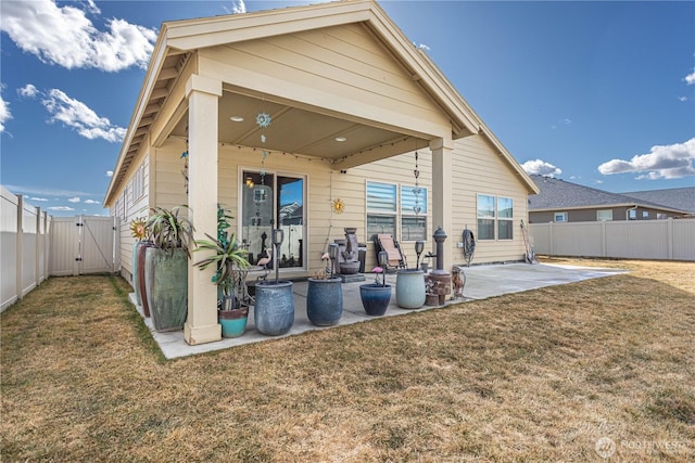 rear view of property featuring a patio area, a lawn, a fenced backyard, and a gate