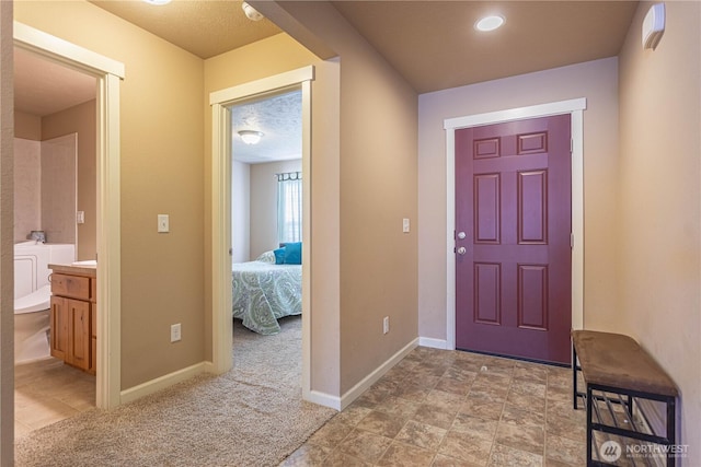 entryway with baseboards, light colored carpet, and a textured ceiling