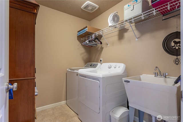 washroom with visible vents, laundry area, a sink, a textured ceiling, and washing machine and dryer