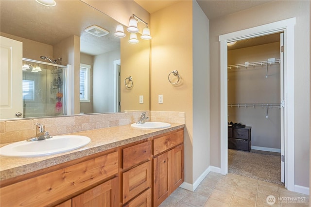 bathroom with tile patterned flooring, visible vents, a shower stall, and a sink