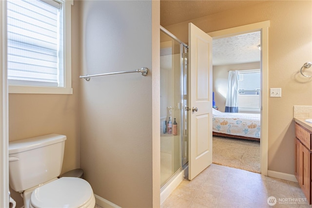 ensuite bathroom with vanity, a shower stall, ensuite bathroom, a textured ceiling, and toilet