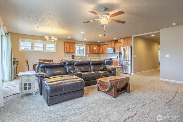 living area featuring recessed lighting, light colored carpet, ceiling fan with notable chandelier, and baseboards