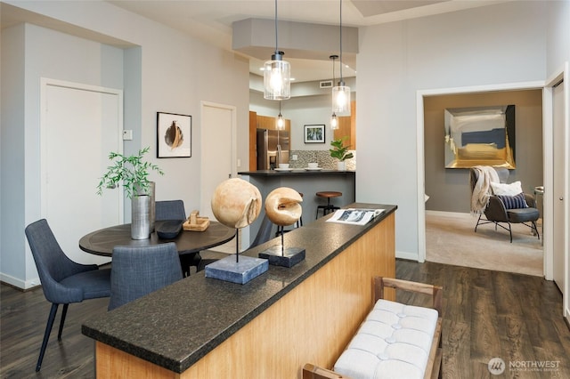 interior space with tasteful backsplash, dark countertops, dark wood-type flooring, stainless steel fridge, and baseboards