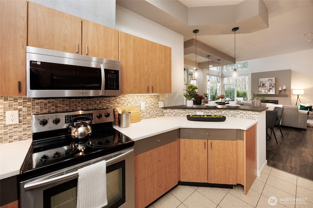 kitchen with a peninsula, stainless steel appliances, decorative backsplash, and open floor plan