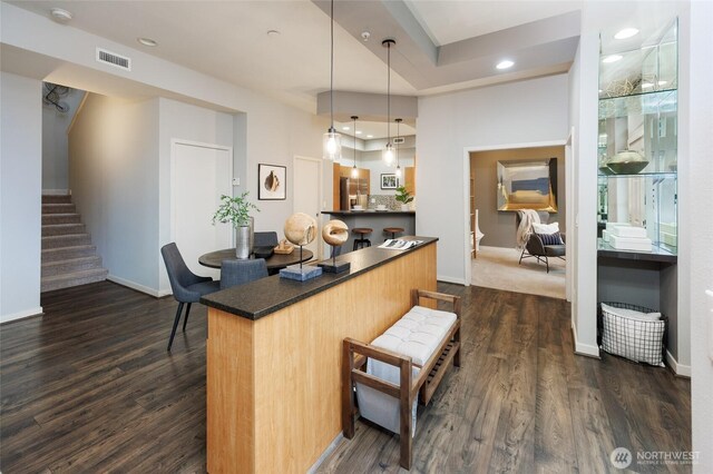 kitchen featuring dark wood-style flooring, visible vents, baseboards, dark countertops, and pendant lighting